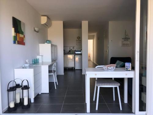 uma cozinha com uma mesa branca, uma mesa e cadeiras em Appartement les Pieds dans l'eau ! em Le Lavandou