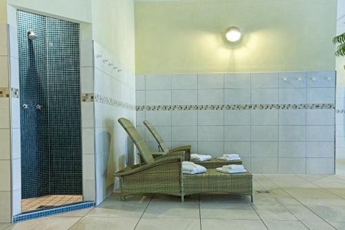 a bathroom with two wicker chairs and a shower at Fletcher Familiehotel Paterswolde in Eelde-Paterswolde