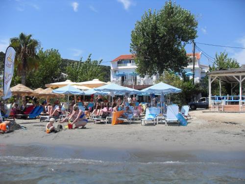 a group of people sitting on a beach with umbrellas at Hercules Sea Front Studios in Katelios