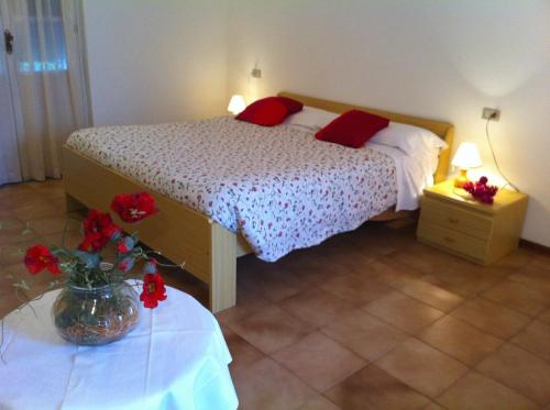 a bedroom with a bed with red pillows and a vase with red flowers at Residence Geranio in Domaso