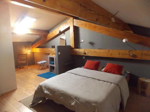 a bedroom with a large bed with two red pillows at La Rosière in Auzelles