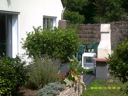 un jardín con un banco y algunos arbustos y una valla en Soizic' house en Trébeurden