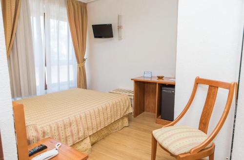 a bedroom with a bed and a chair and a desk at Hotel Las Anclas in El Astillero