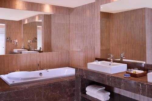 a bathroom with two sinks and a tub and a mirror at Jaz Crystal, Almaza Bay in Marsa Matruh