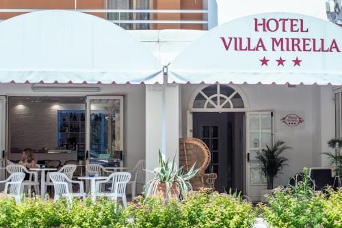 a hotel villa mireka with tables and chairs under an umbrella at Villa Mirella-NUOVA GESTIONE in Grado