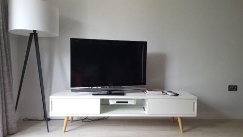 a tv on a white entertainment center with a lamp at Great Northern Road Apartment in Cambridge