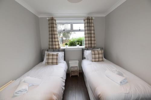 two twin beds in a room with a window at Sighthill 3 Bedrooms with Private Garden in Edinburgh