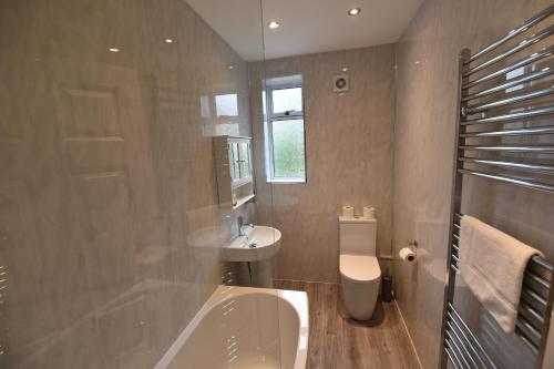 La salle de bains est pourvue d'une baignoire, d'un lavabo et de toilettes. dans l'établissement Sighthill 3 Bedrooms with Private Garden, à Édimbourg