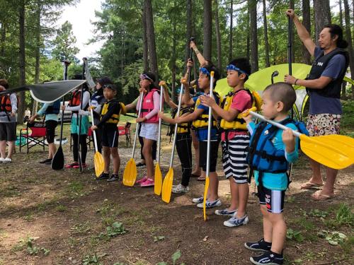 a group of children holding paddles in a forest at Hotel Mumon in Myoko