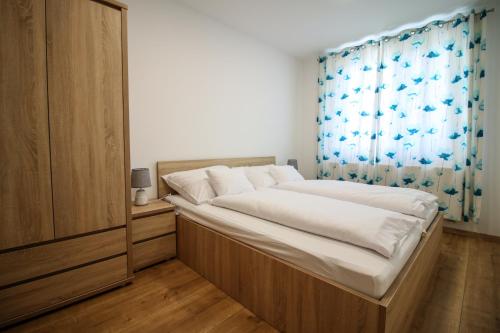 a bedroom with a large bed with a blue curtain at Napfény Apartman in Sopron