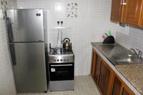 a kitchen with a stainless steel refrigerator and a stove at Al Noor Furnished Flats in Salalah