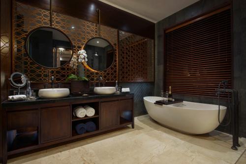 a bathroom with two sinks and a tub and two mirrors at Samsara Ubud in Ubud