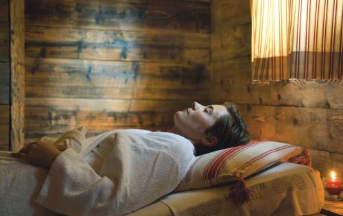 a woman laying in a bed in a room at Chalet-Hôtel La Marmotte, La Tapiaz & SPA, The Originals Relais in Les Gets