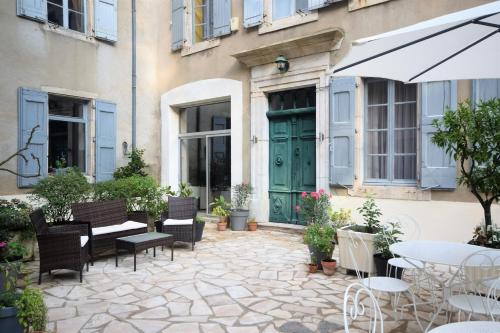 een patio met stoelen en tafels en een groene deur bij Maison De l'Aguze in Saint-Pons