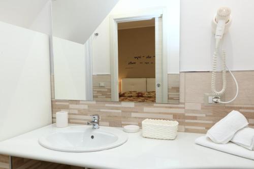 een badkamer met een witte wastafel en een spiegel bij La Casetta del Borgo Cefalù in Cefalù