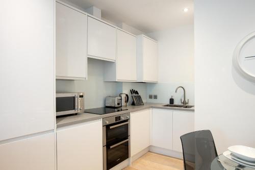 una cucina bianca con armadi bianchi e lavandino di Hampden Apartments - The George a Windsor