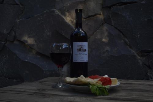 a bottle of wine and a plate of food and a glass at JR's House in Yerevan