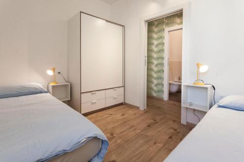um quarto branco com 2 camas e um espelho em Casa "Le Mura" 70mq em Riva del Garda