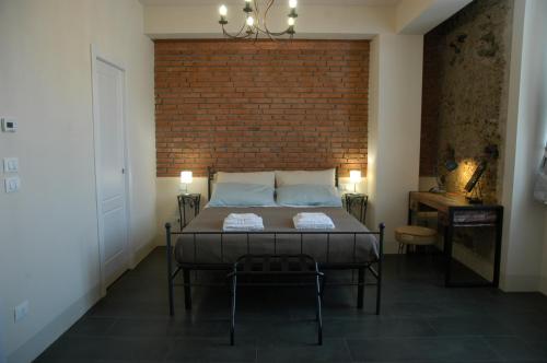 a bedroom with a bed and a brick wall at Castello D'Alcontres Guest House 3 stelle in Nizza di Sicilia