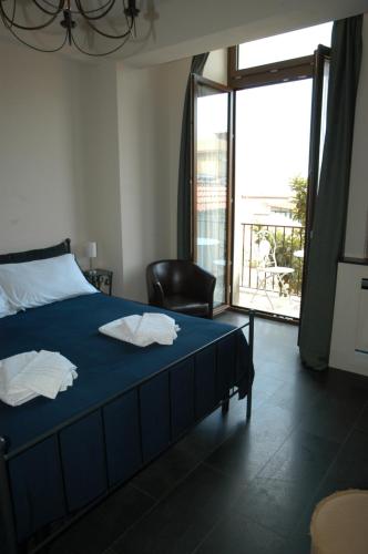 a bedroom with a blue bed with a chair and a window at Castello D'Alcontres Guest House 3 stelle in Nizza di Sicilia