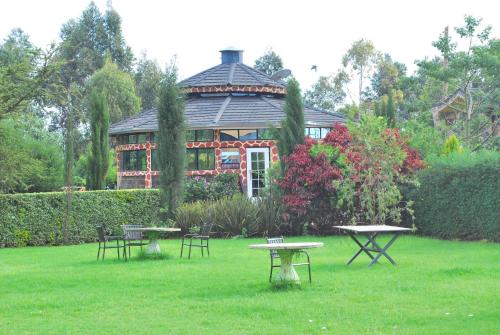 a house with tables and chairs in a yard with a building at Misty Mountain Lodge in Naro Moru
