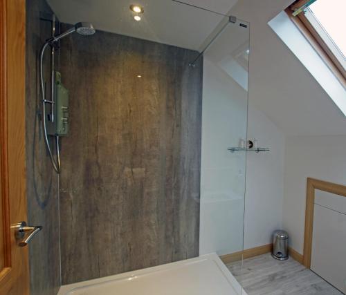 een douche met een glazen deur in de badkamer bij Cameron Cottage in Inverkip