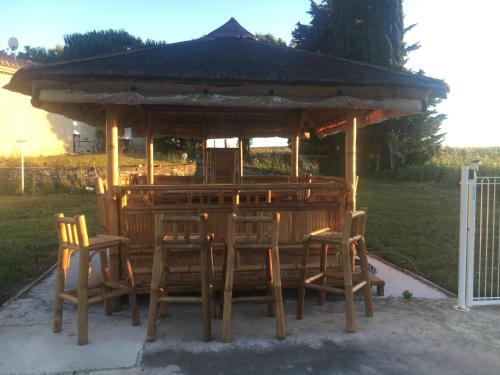 a wooden gazebo with chairs and a table at Les Gites De La Serre in Saint-Thibéry