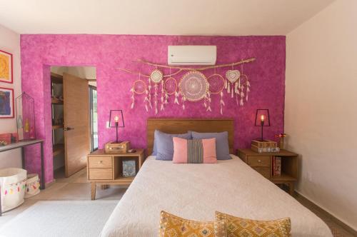 um quarto com uma cama grande e uma parede roxa em Casa Malva em Sayulita