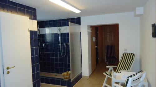 a bathroom with a shower with blue tiles on the wall at Hotel Fortuna in Heringsdorf