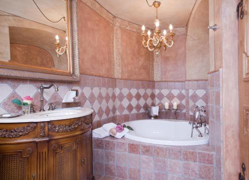 a bathroom with a tub and a sink and a chandelier at Schloss Matzen in Reith im Alpbachtal