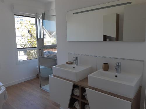 a white bathroom with two sinks and a mirror at le vergoyer in Calais