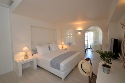 a white bedroom with a bed and a television at Villa Marandi Luxury Suites in Stelida