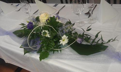 a white table with a centerpiece of flowers and wine glasses at Penzion Slunečno in Dobšín