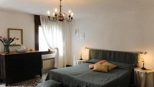 a bedroom with a green bed and a chandelier at Abitazione Morosini Apartment in Venice