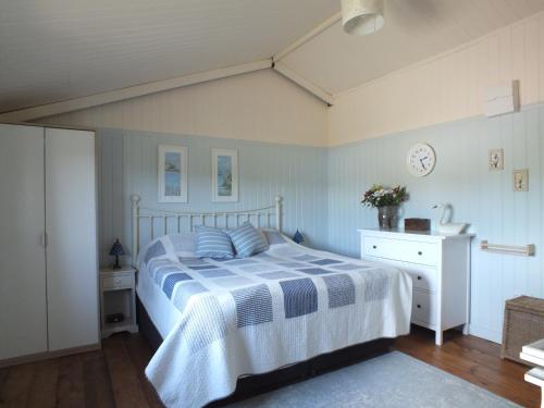 a bedroom with a bed with a blue and white blanket at The Potting Shed And The Garden Shed Self Catering in Carmarthen