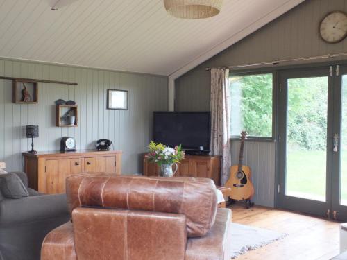 a living room with a leather couch and a guitar at The Potting Shed And The Garden Shed Self Catering in Carmarthen