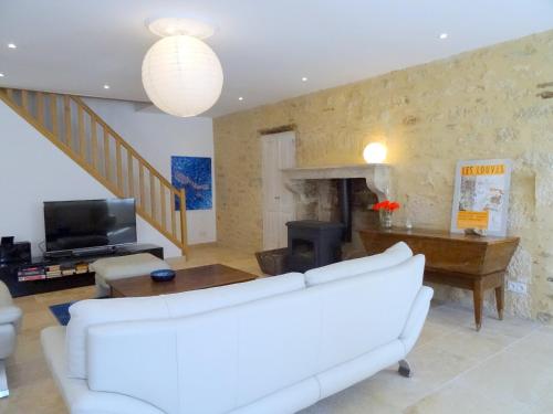 un salon avec un canapé blanc et une télévision dans l'établissement La Cour, à Flavigny-sur-Ozerain