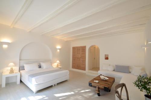a white bedroom with two beds and a table at Villa Marandi Luxury Suites in Stelida