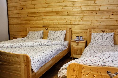 a bedroom with two beds and a wooden wall at Chata u Petrenkov in Horná Turecká