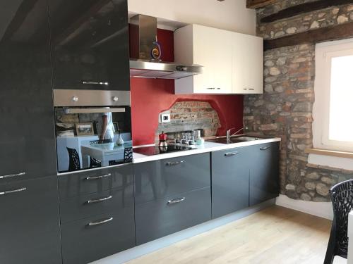 a kitchen with gray cabinets and a brick wall at Casa In Piazza in Cividale del Friuli