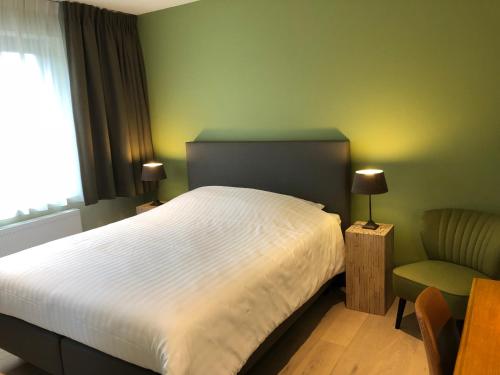 una camera con un letto bianco e una sedia di B&B Garden55 a Mechelen