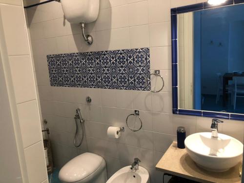 een badkamer met een wastafel, een toilet en een spiegel bij Villa del Sole in Capri
