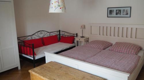 ラーデボイルにあるUferlosのベッドルーム1室(赤い枕とテーブル付きのベッド2台付)