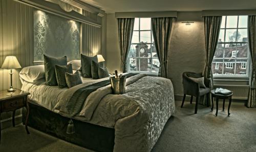a bedroom with a large bed and two windows at The George Inn in Robertsbridge