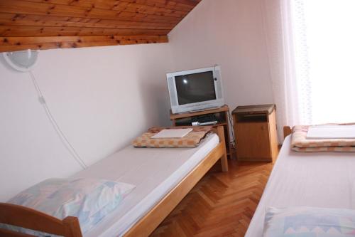 um pequeno quarto com duas camas e uma televisão em Apartments Jaska em Pag
