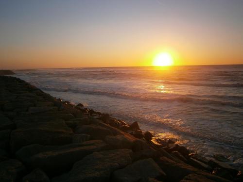 a sunset over the ocean with a rocky beach at Sun, Sky and Sea in Esmoriz