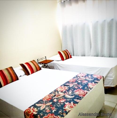two beds in a room with white walls at Hotel Pousada Riacho da Areia in Águas de Lindóia