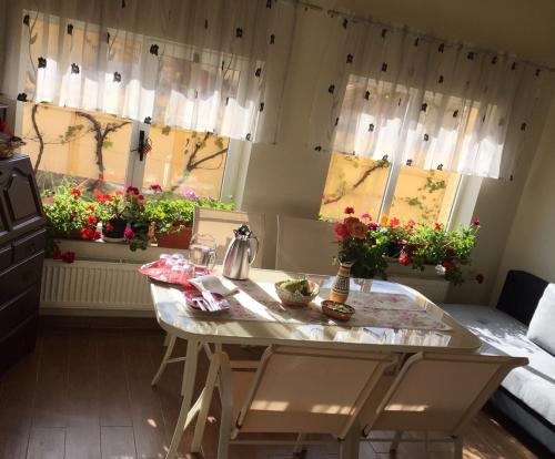 een keuken met een tafel en 2 ramen met bloemen bij Casa Florea in Avrig