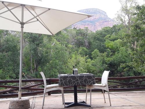 a table and chairs with an umbrella on a deck at Moholoholo Ya Mati in Kampersrus AH