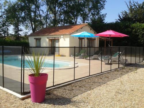 a fence with a potted plant and umbrellas next to a pool at Château de Bournand B&B in Bournand